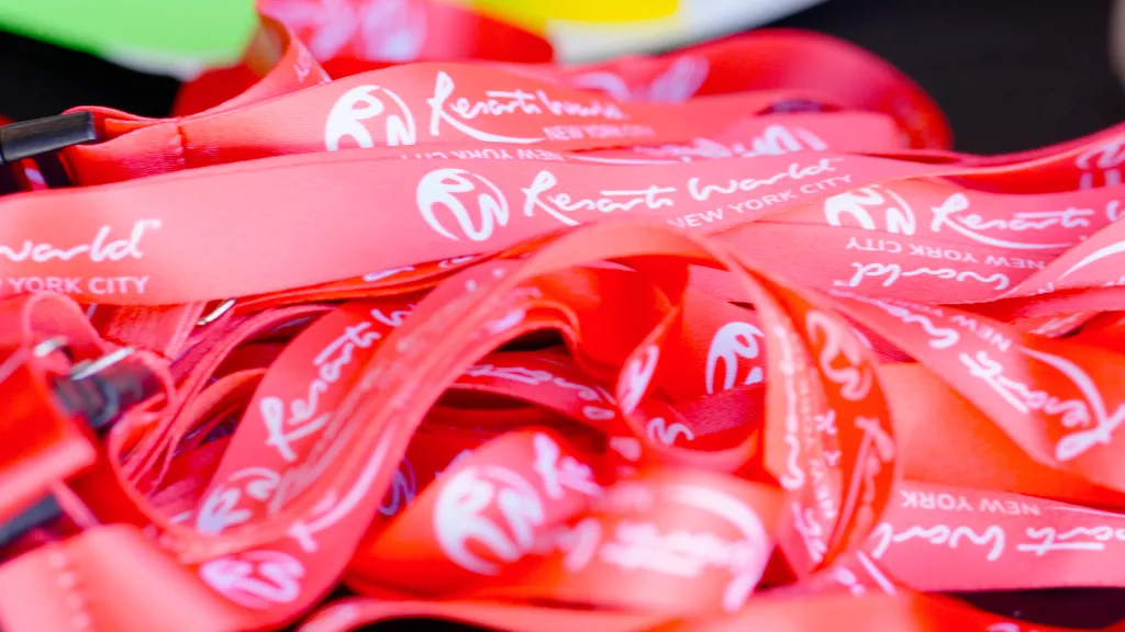 Close-up of red lanyards with white "Resorts World New York City" logos.