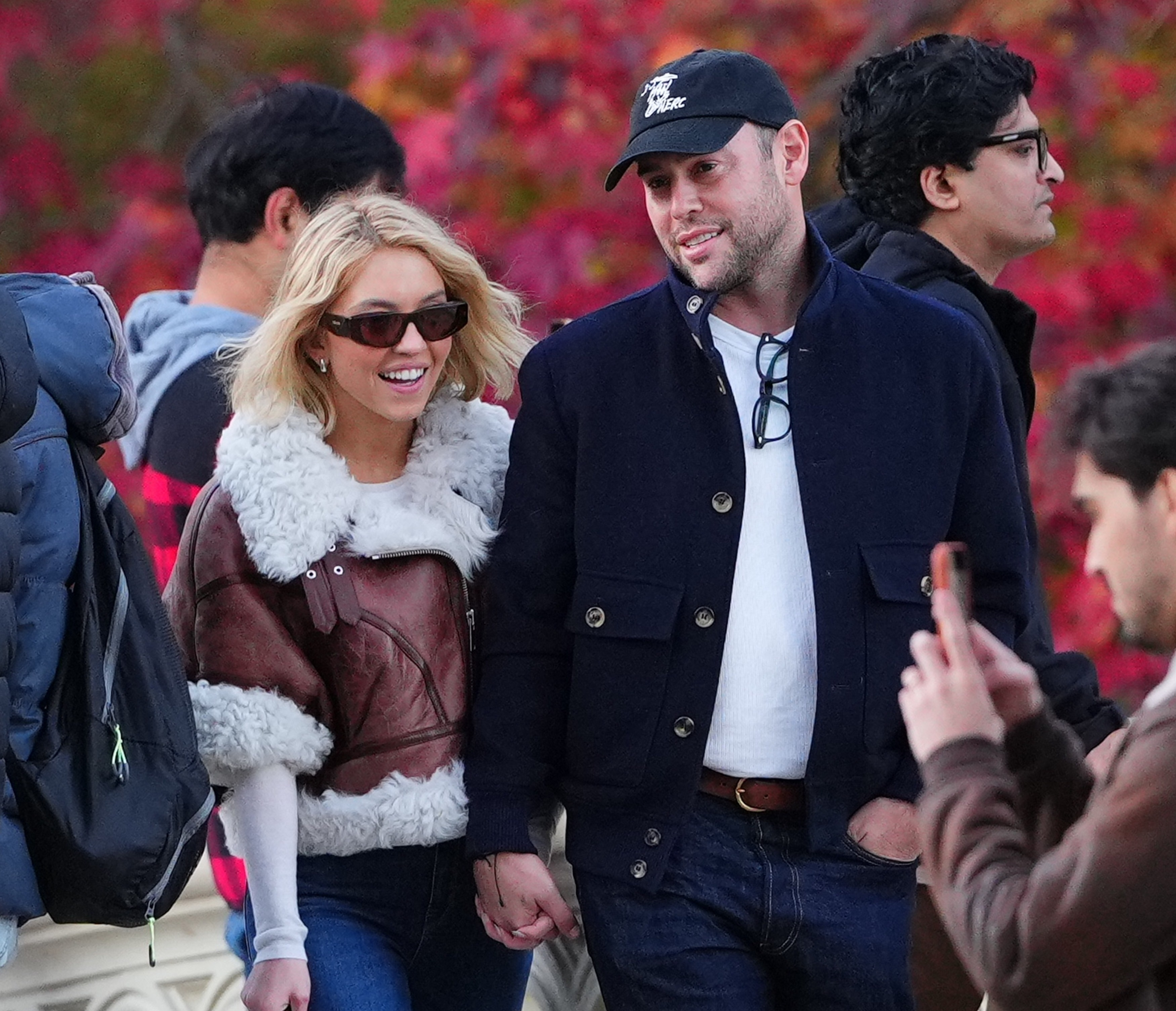 Sydney Sweeney and Scooter Braun walking hand-in-hand across Bow Bridge in Central Park.