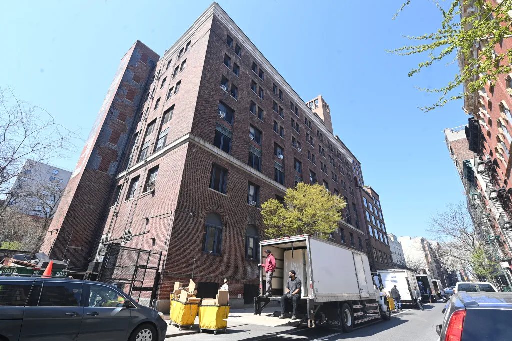 Bellevue men's shelter, a large brick building covered in scaffolding, on a city street.