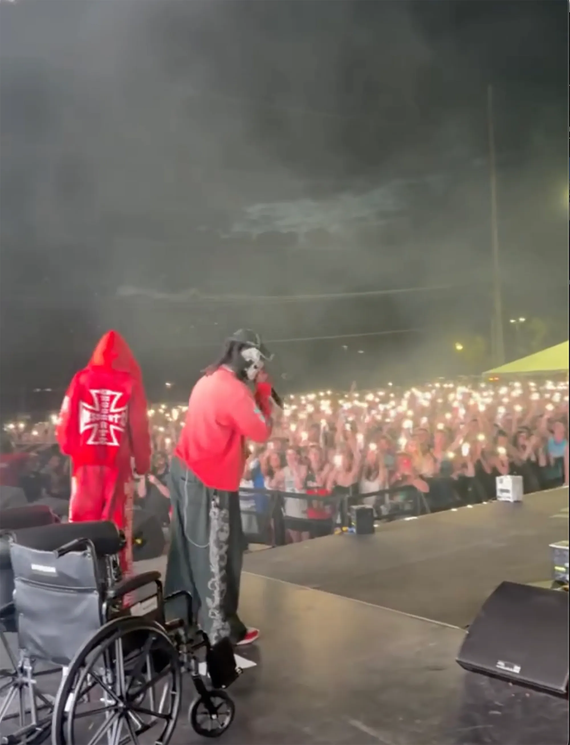 Offset performs on stage in front of a crowd, having left his wheelchair behind him.