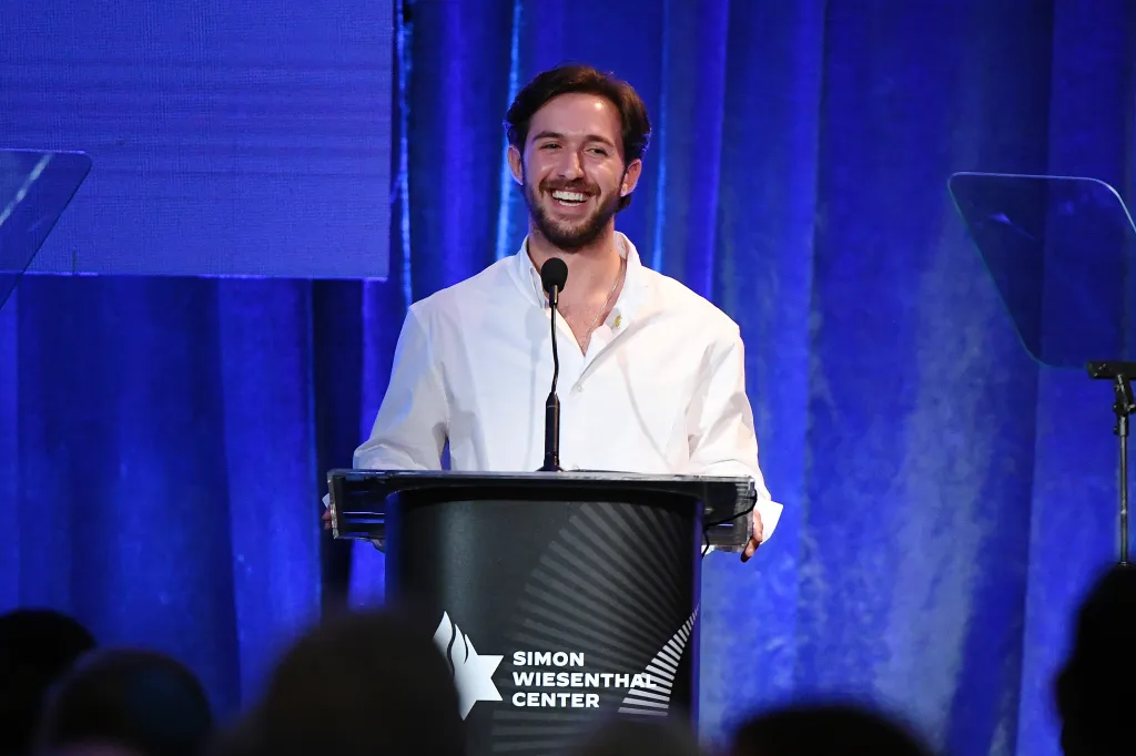 Omer Shem Tov smiling while speaking onstage at the Simon Wiesenthal Center event.