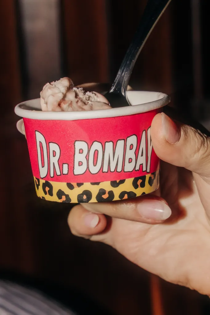A hand holds a cup of Dr. Bombay ice cream.