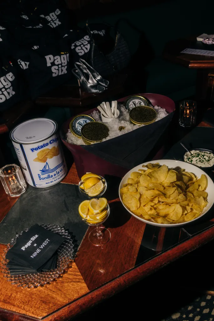 Table with "Page Six" branded napkins, potato chips, and caviar on ice.