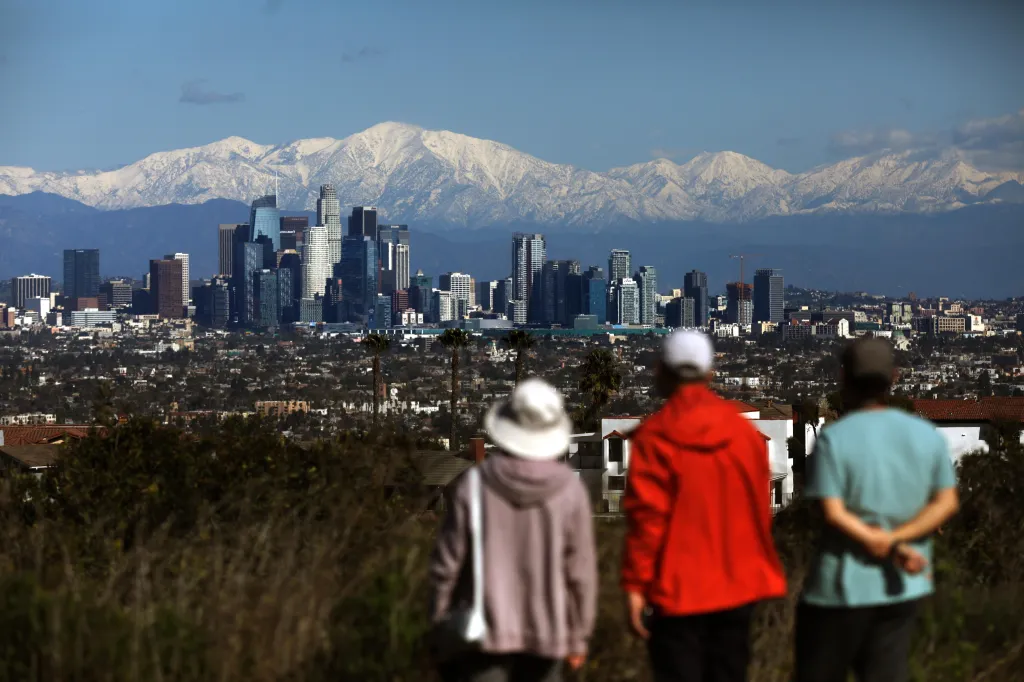 People view the Los Angeles skyline and snow-capped San Gabriel mountains.