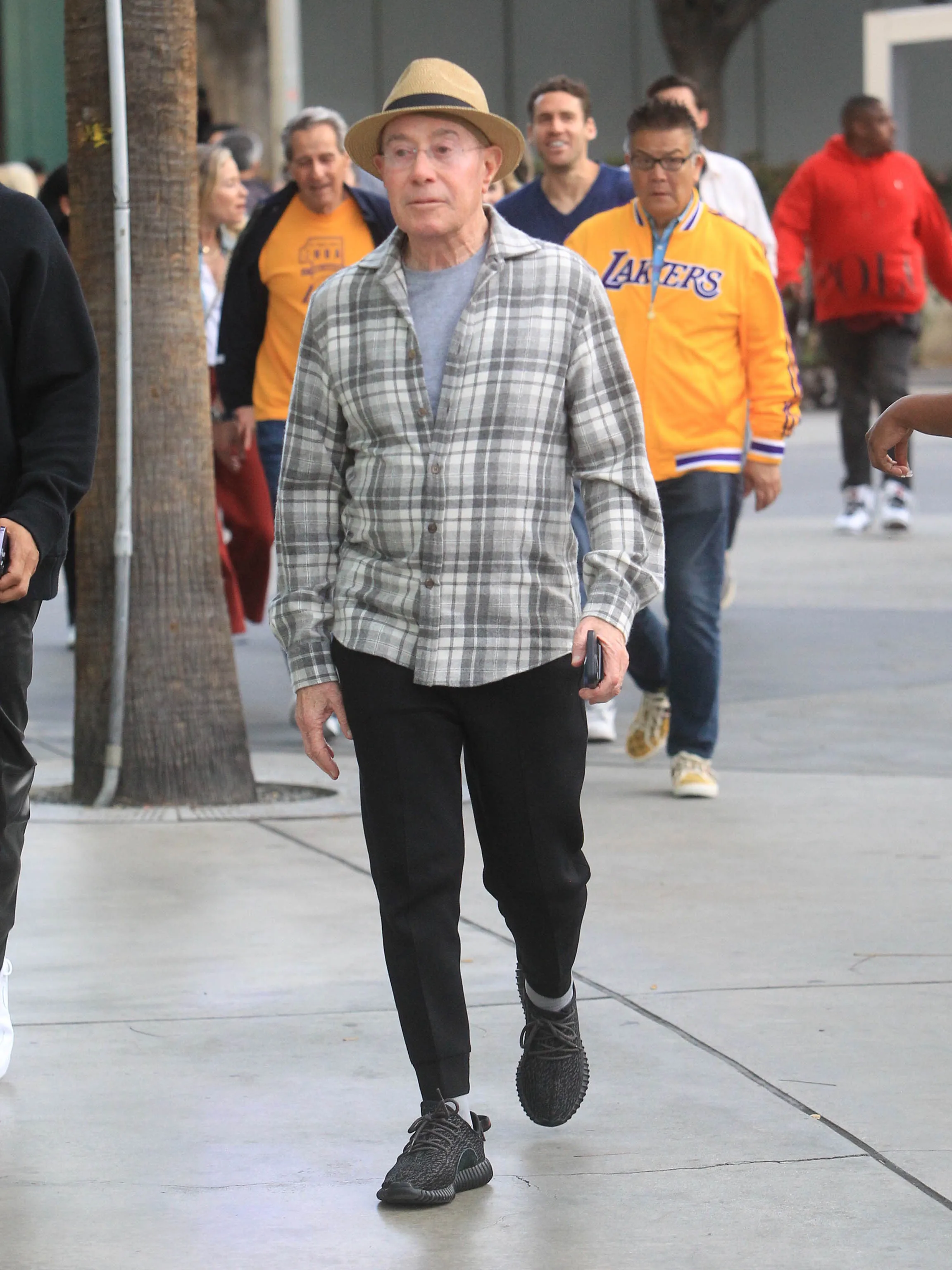 David Geffen walking outdoors with a phone in his hand.