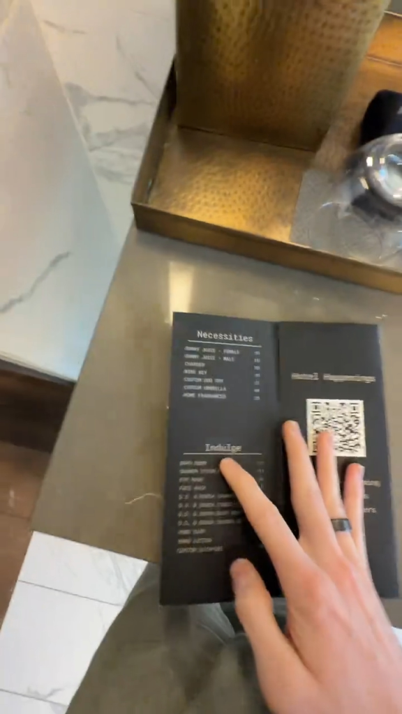 A person's hand pointing at a hotel's menu of 