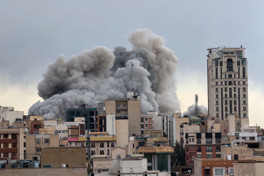 A plume of smoke rises above buildings in Tehran, Iran.