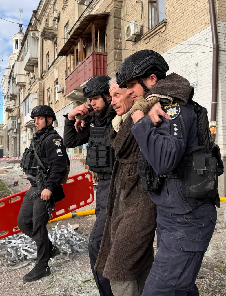 Police officers evacuate a wounded resident in Dnipro, Ukraine, following a Russian drone and missile strike.