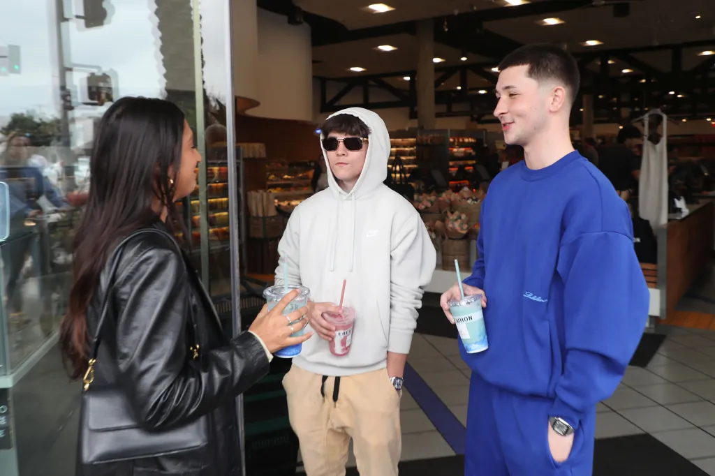 Two men and one woman holding drinks at Erewhon in Beverly Grove.