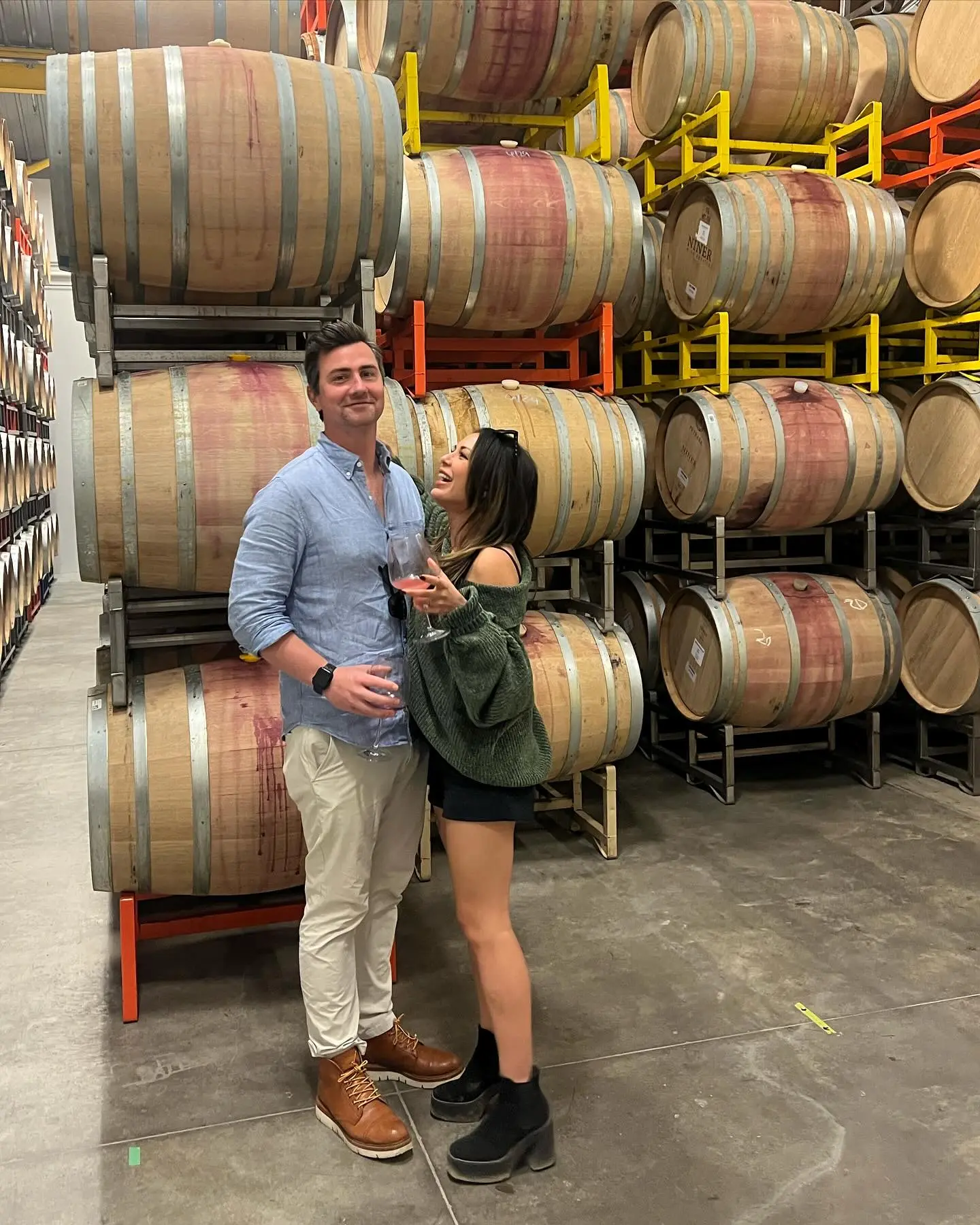 Janel Parrish and Chris Long smiling in a wine cellar.