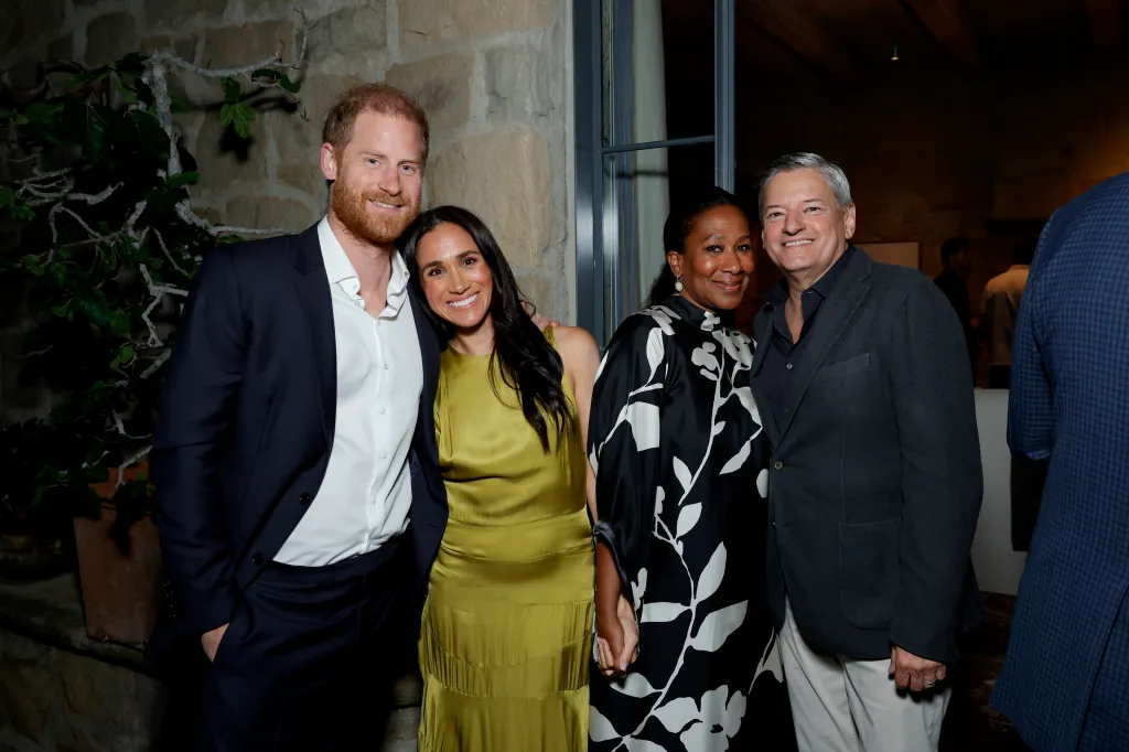 Prince Harry, in a navy blue suit and white shirt, Meghan Markle, in a chartreuse silk dress, Nicole Avant, in a black and white patterned dress, and Ted Sarandos, in a navy blue blazer, blue shirt, and khaki pants, posing at the Netflix BEEF Season 2 Montecito Tastemaker.