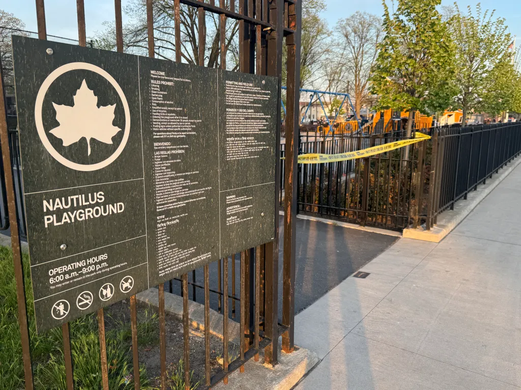 A sign for Nautilus Playground with yellow caution tape across the entrance to the playground.