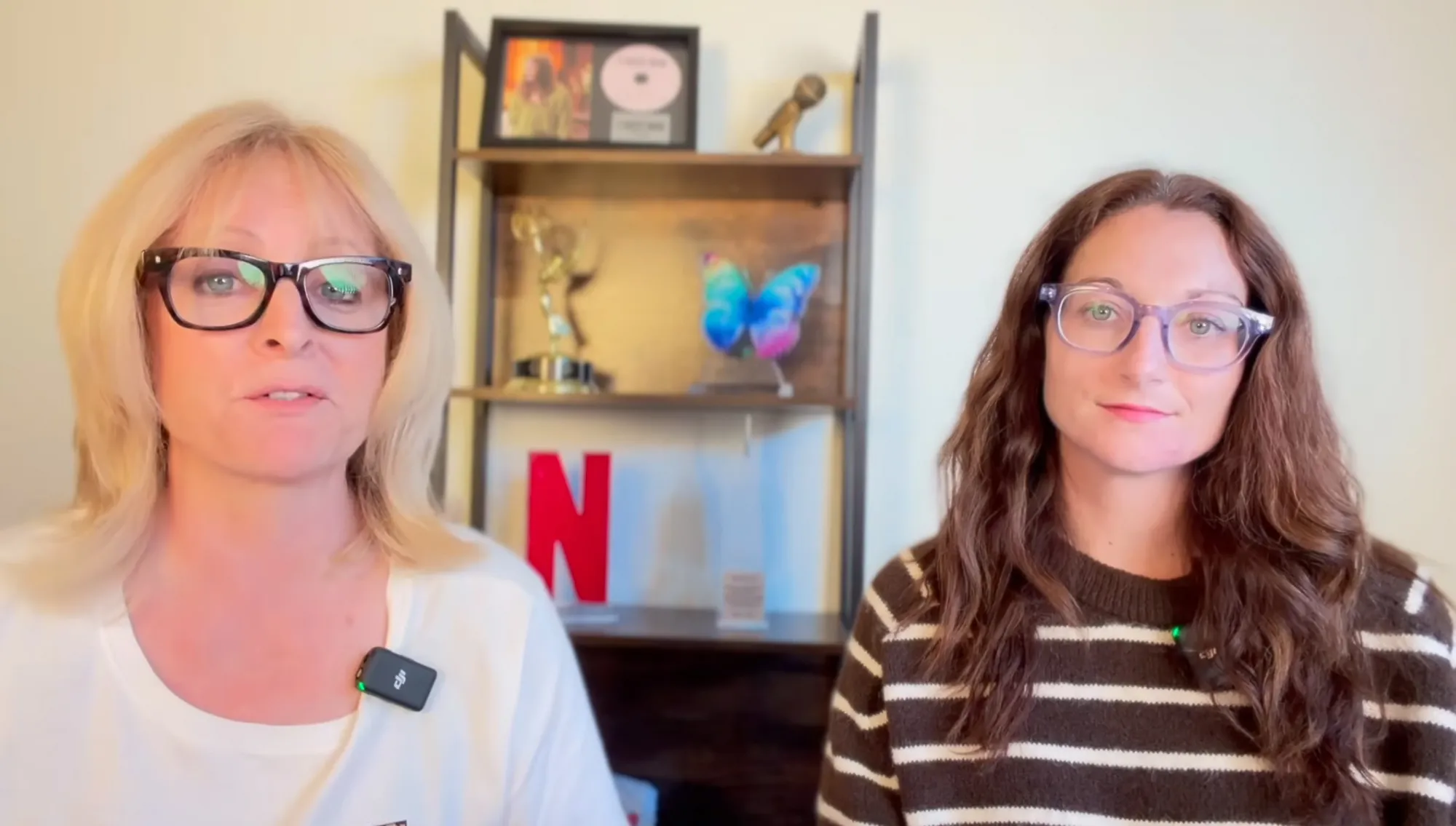 Two women, one blonde and one with brown hair, in front of a shelf with an Emmy award and a Netflix "N".
