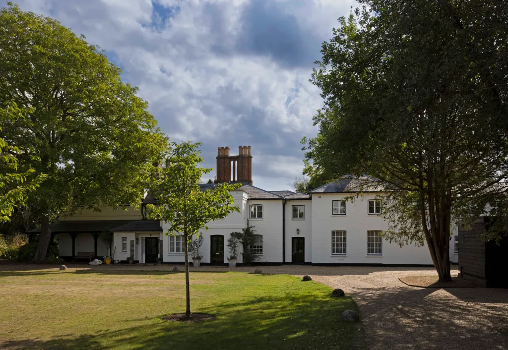 Frogmore Cottage, a white brick house with multiple chimneys and windows, surrounded by trees and green grass.