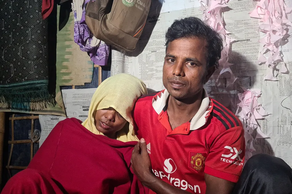 Rachel Begum, who was rescued from a capsized boat, sits inside her shelter at a refugee camp in Ukhia, with a man.