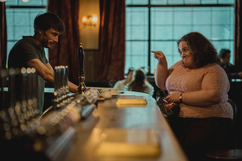 Richard Gadd, behind a bar, looks down as Jessica Gunning points at him.