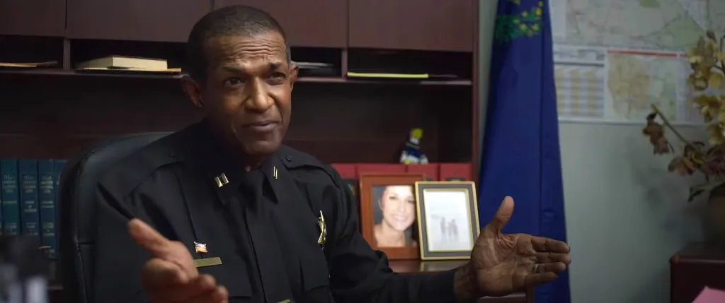 Rif Hutton as a police chief in a black uniform.