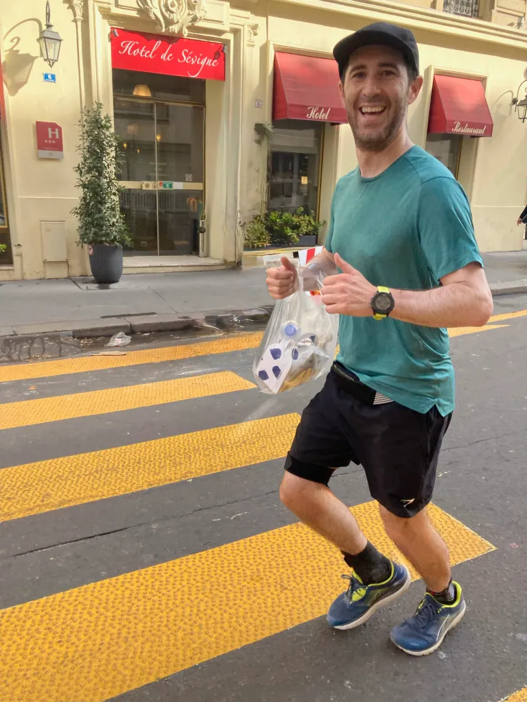 Runner Andy Solarz holding a bag of trash while giving a thumbs up.