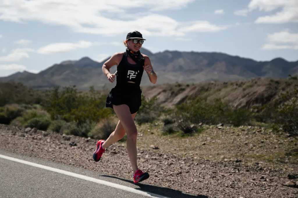 Molly Baker running on a road with mountains in the background.