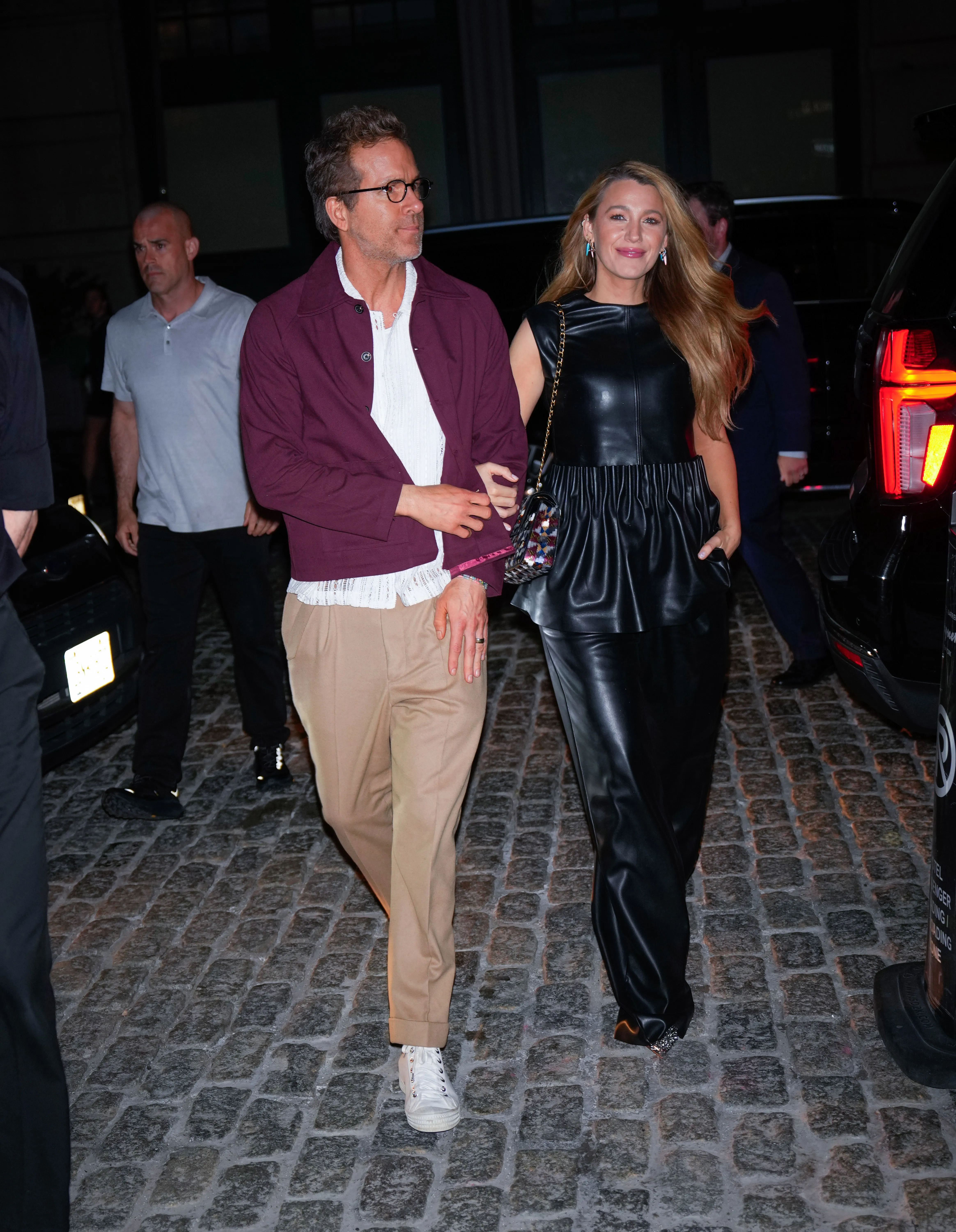 Ryan Reynolds and Blake Lively walk arm-in-arm on a cobblestone street.