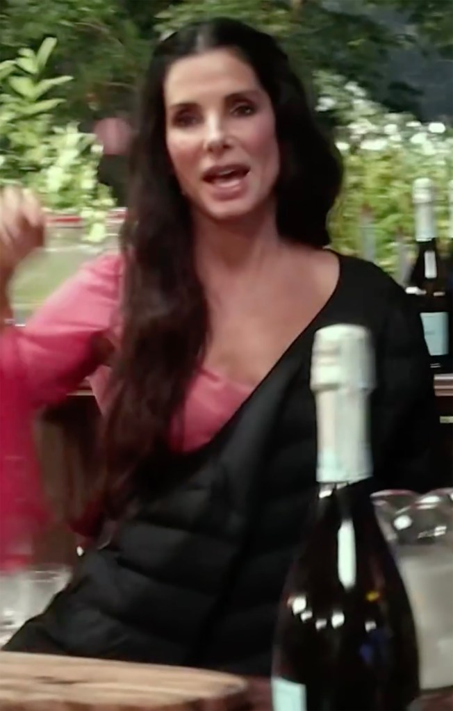 Sandra Bullock, wearing a pink top and black jacket, smiles while talking.
