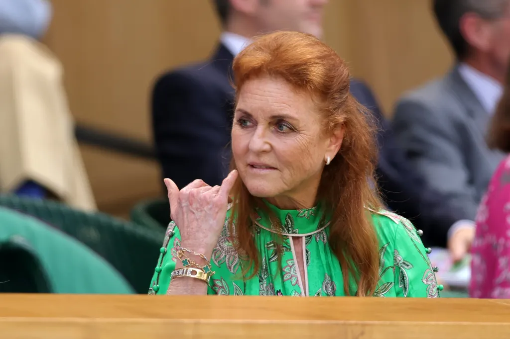 Sarah Ferguson, Duchess of York, wearing a green patterned dress and bracelets, sits in the Royal Box at Wimbledon.