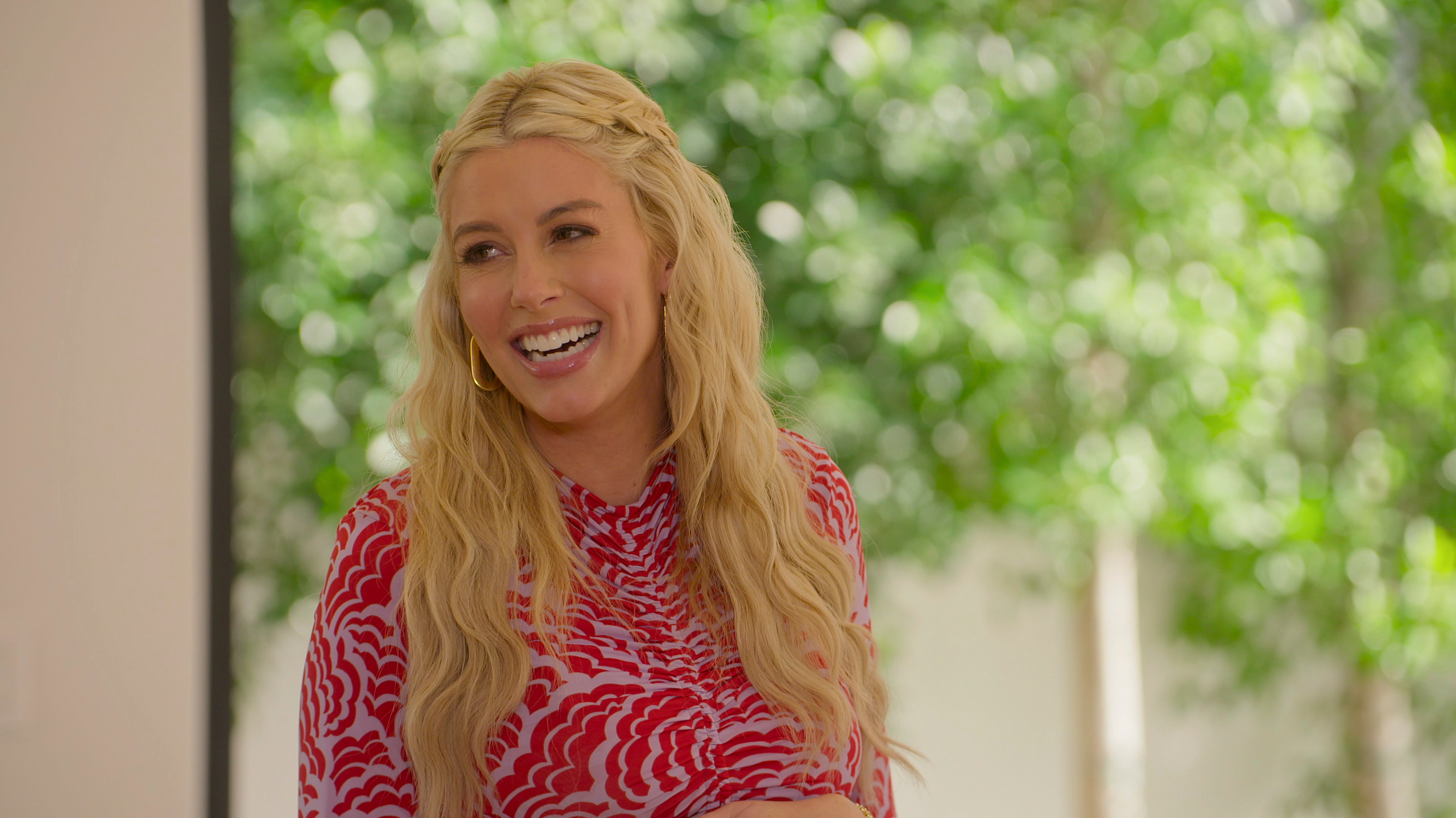 Heather Rae laughing in a red and pink patterned top.