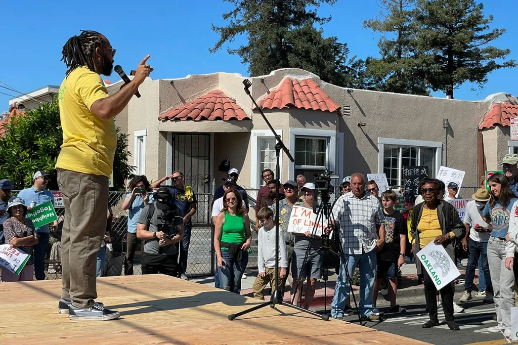 Seneca Scott speaking to a crowd of people at an outdoor event.