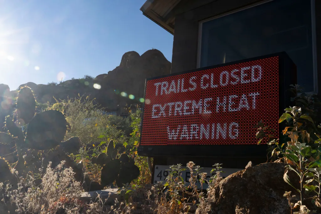 A sign warning "TRAILS CLOSED EXTREME HEAT WARNING" at Camelback Mountain.