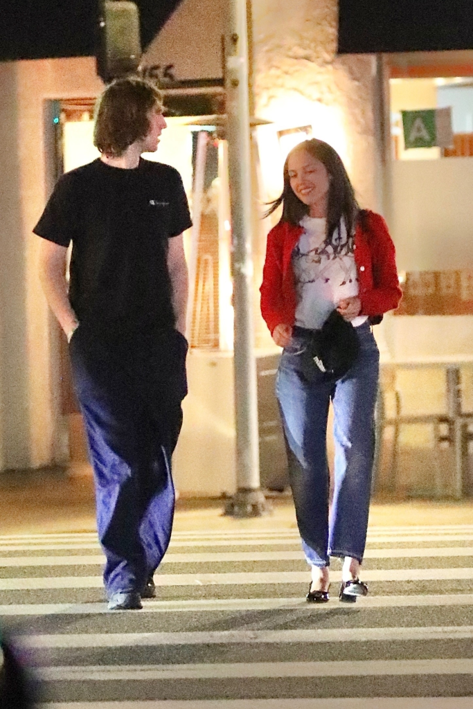 Olivia Rodrigo and Cameron Winter crossing a street at night.
