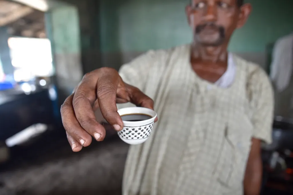 A staff member presenting a cup of coffee.