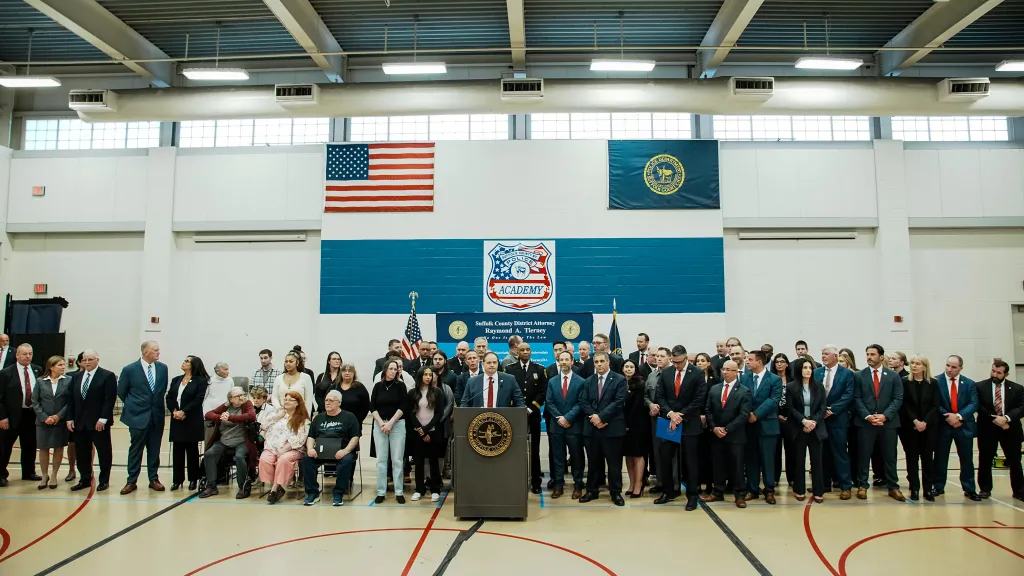 Suffolk County District Attorney Raymond A. Tierney speaking at a news conference with law enforcement and victims' family members present.