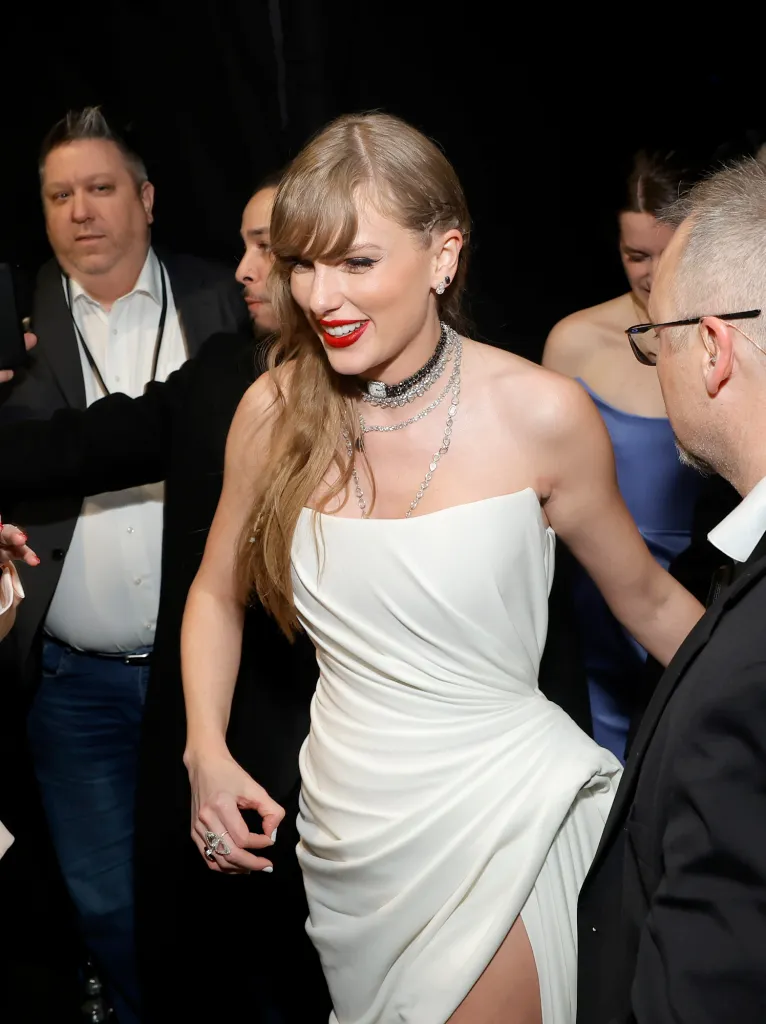 Taylor Swift in a white dress, red lipstick, and necklaces attends the 66th Grammy Awards.