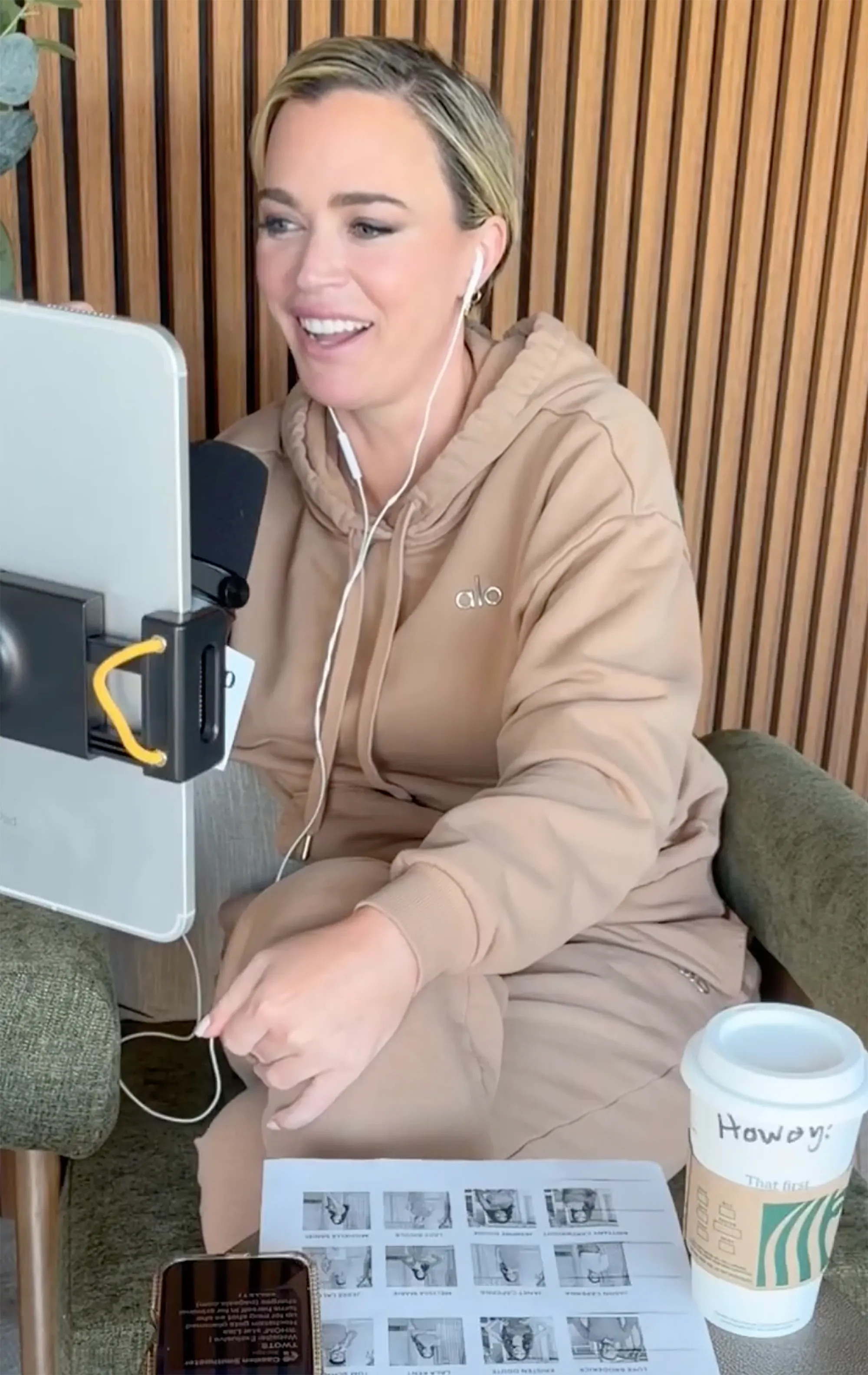 Teddi Mellencamp smiling while sitting and looking at a tablet.