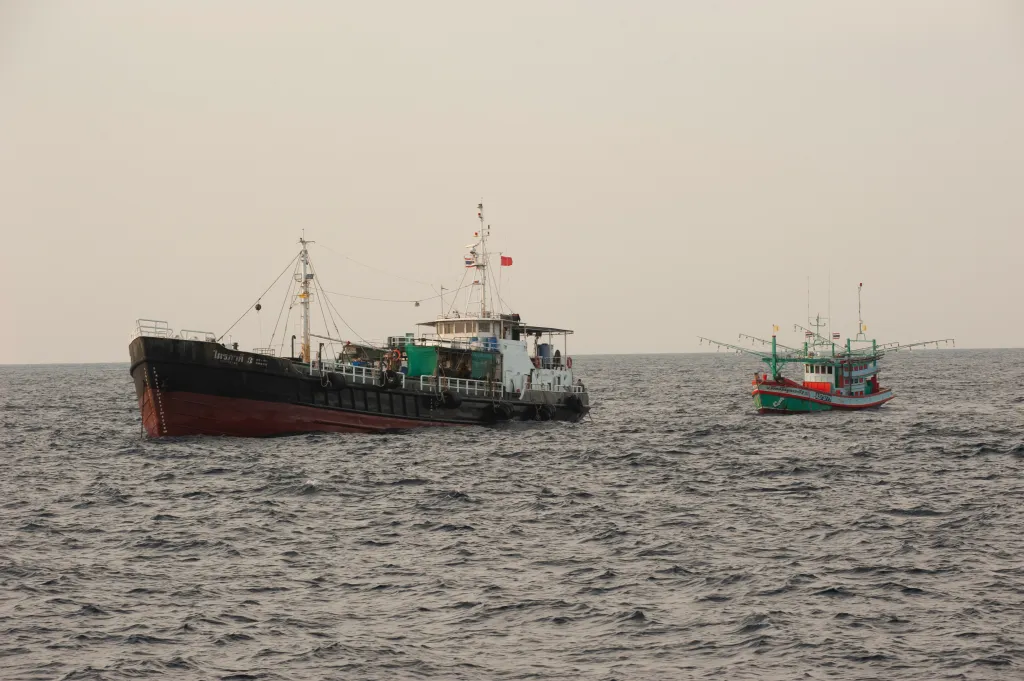 A Thai fishing trawler pulling up to a diesel tanker, offshore from Phuket, Thailand.