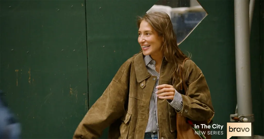 A woman in a brown jacket smiles.