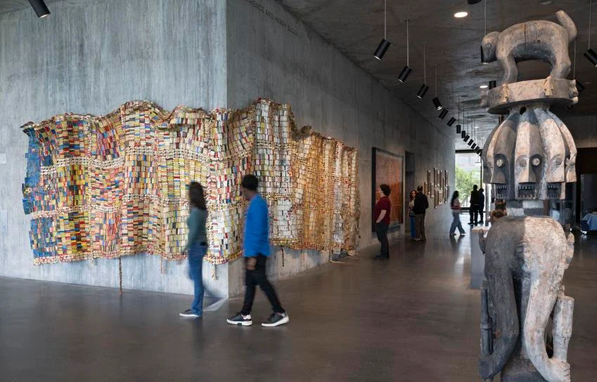 Textile Conversations: Africa and Black America installation view featuring El Anatsui's Fading Scroll, 2007, left, and an Ijo Republic of Nigeria Forest Spirit Figure, early 19th century. Source: Museum Associates/LACMA