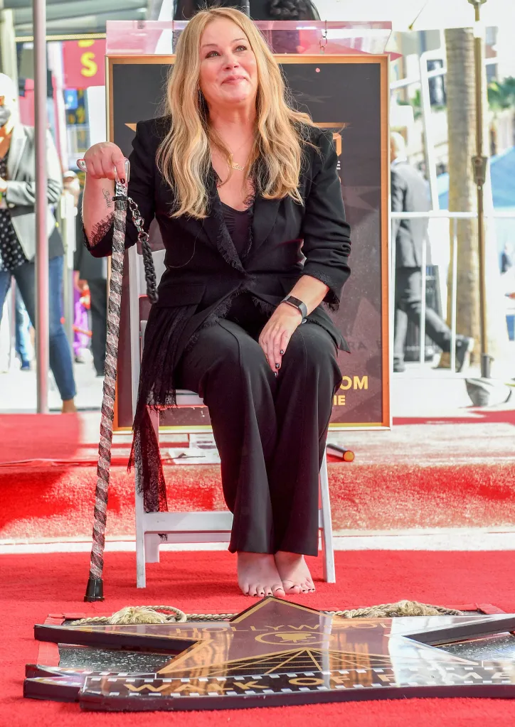 Actress Christina Applegate seated, holding a walking stick, at her Hollywood Walk of Fame star ceremony.
