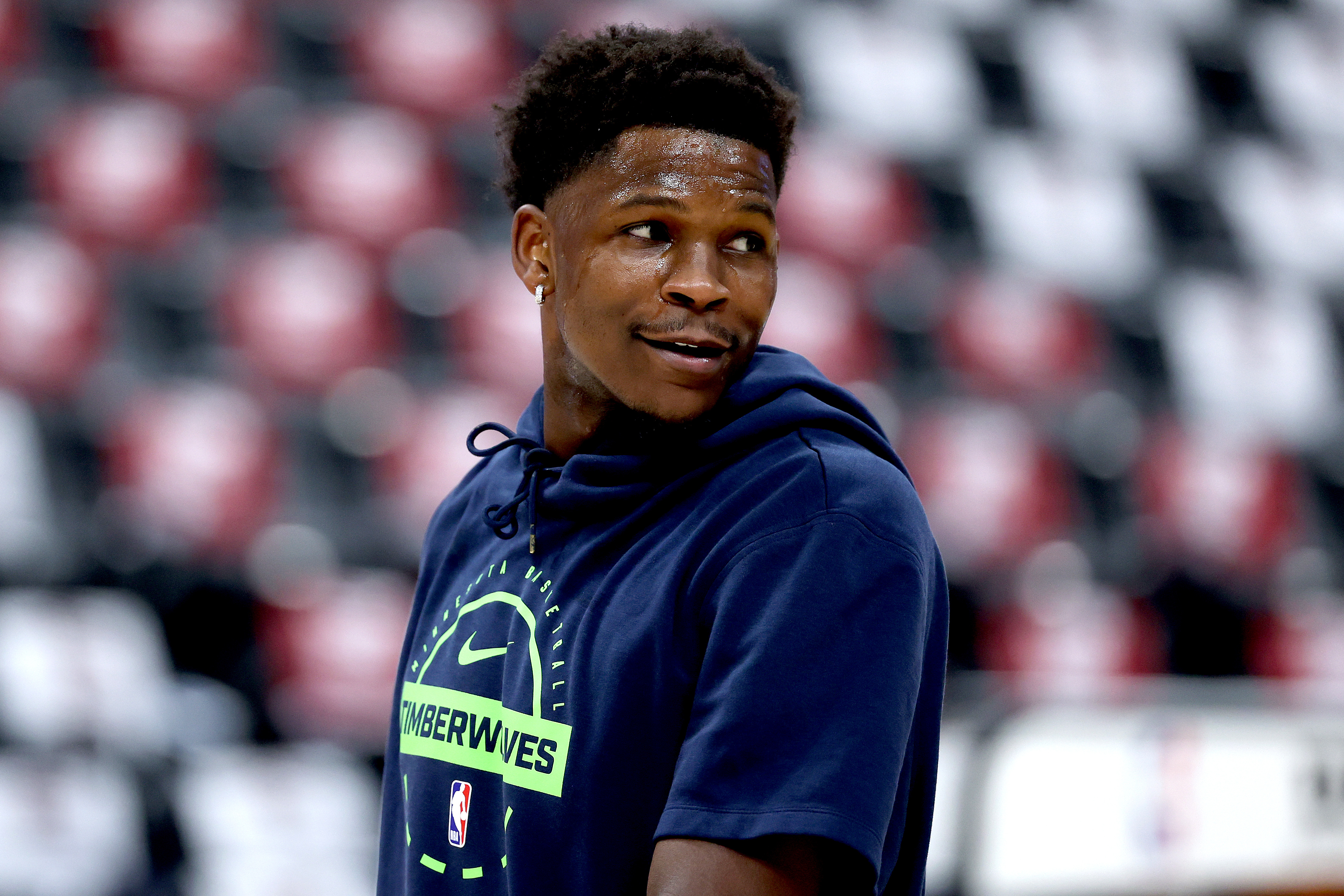 Anthony Edwards of the Minnesota Timberwolves warms up in a navy hoodie with "TIMBERWOLVES" in lime green.
