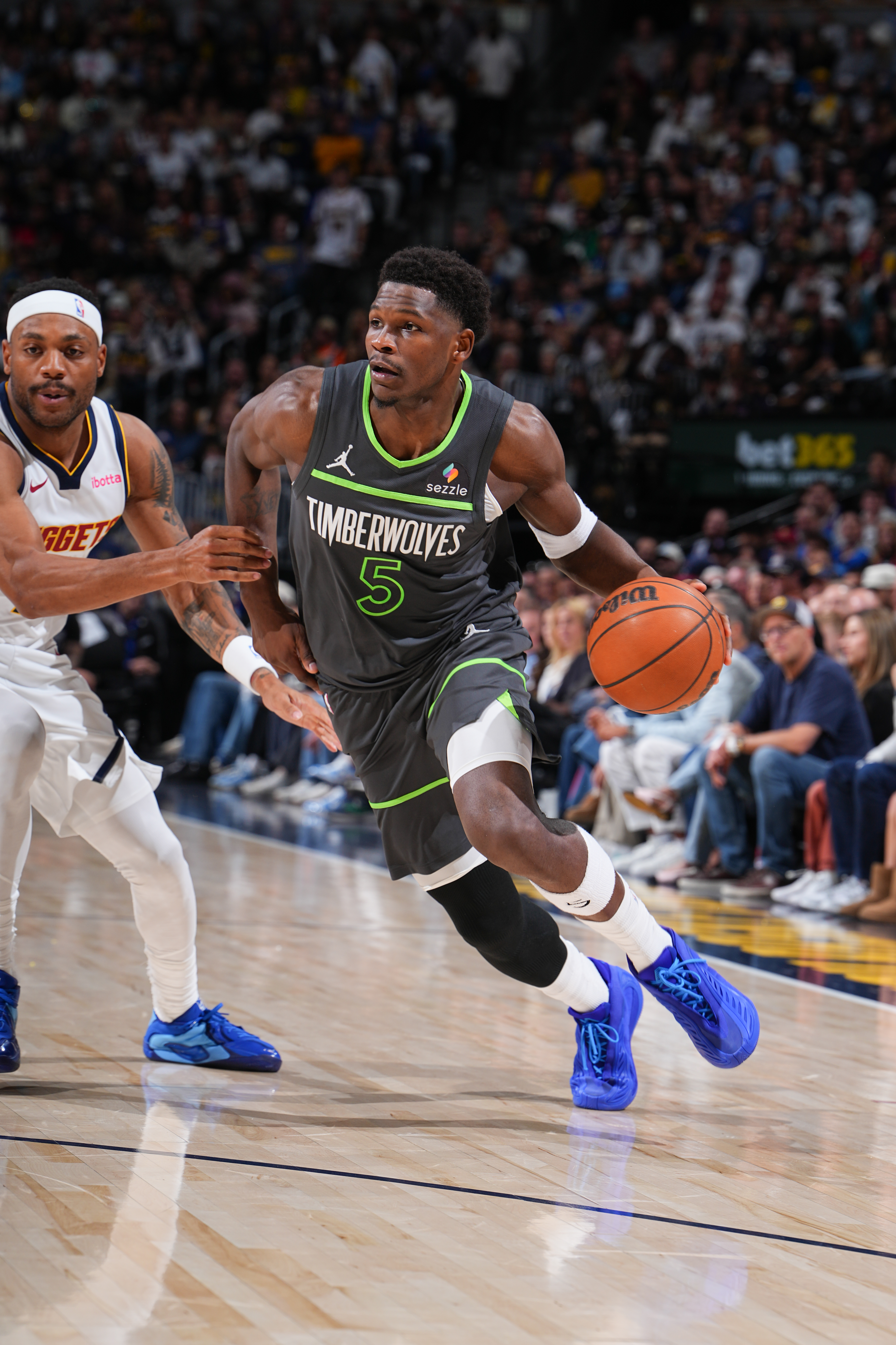 Anthony Edwards dribbles the basketball while being guarded by a Denver Nuggets player.