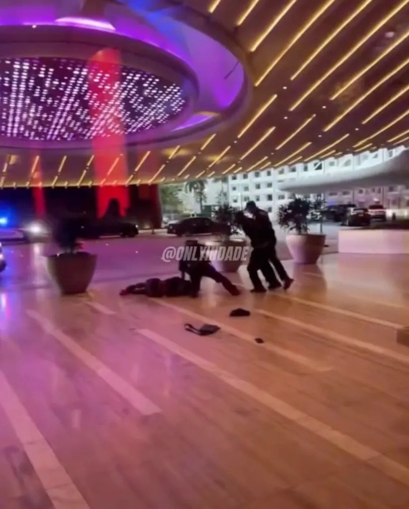 Video grab of a person lying on the ground while another person helps them up, under a brightly lit hotel entrance.