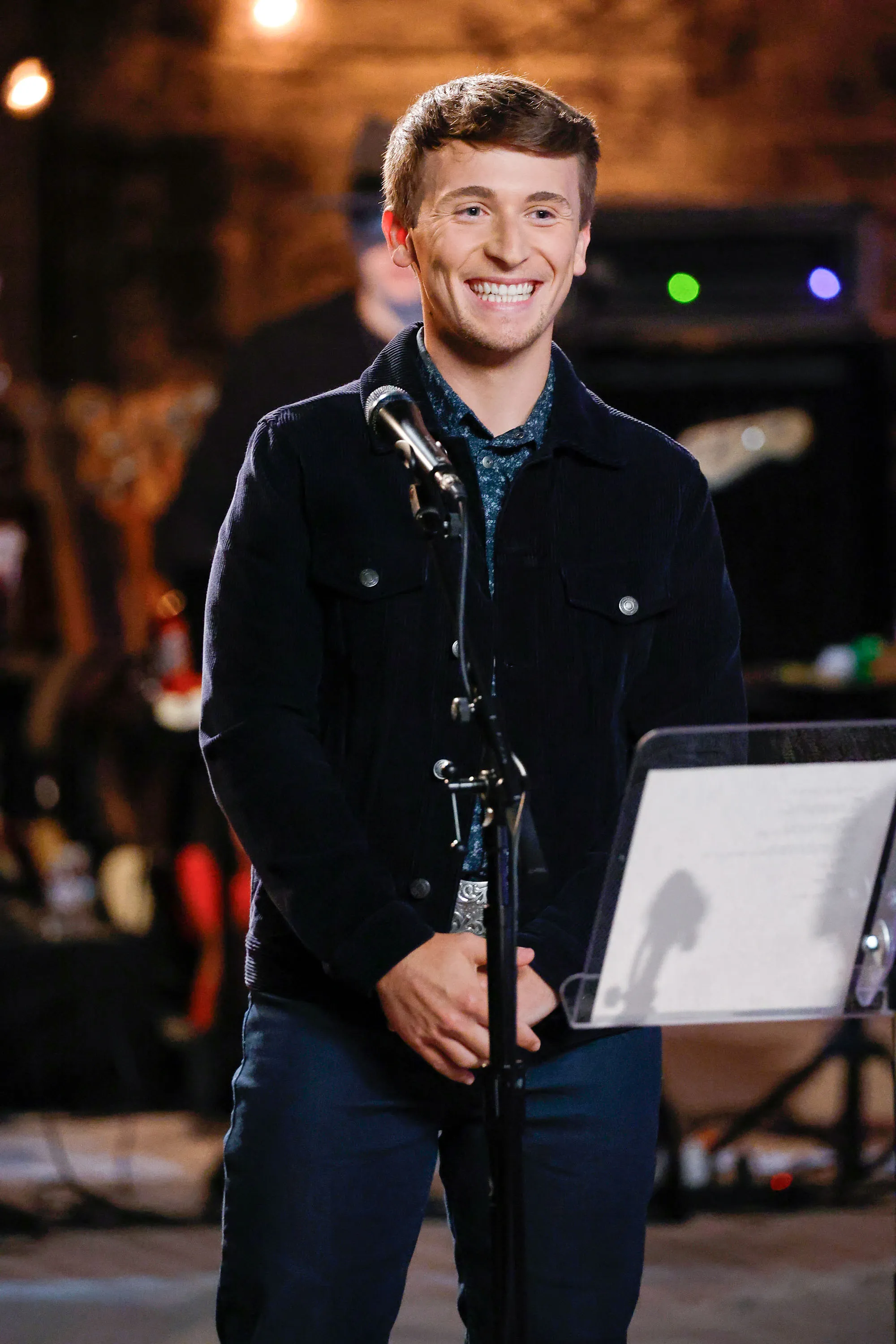 Dylan Carter smiling and standing at a microphone on a stage.