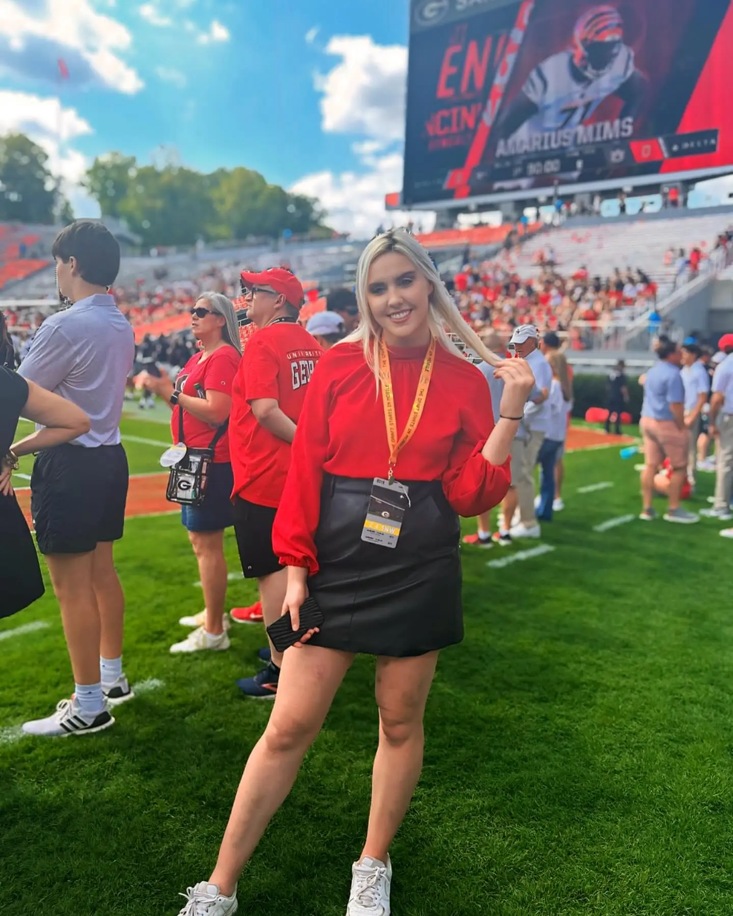 Crissy Froyd smiling in a stadium with a jumbotron showing "GEORGIA VS CINCINNATI" and "AMARIUS MIMS" in the background.