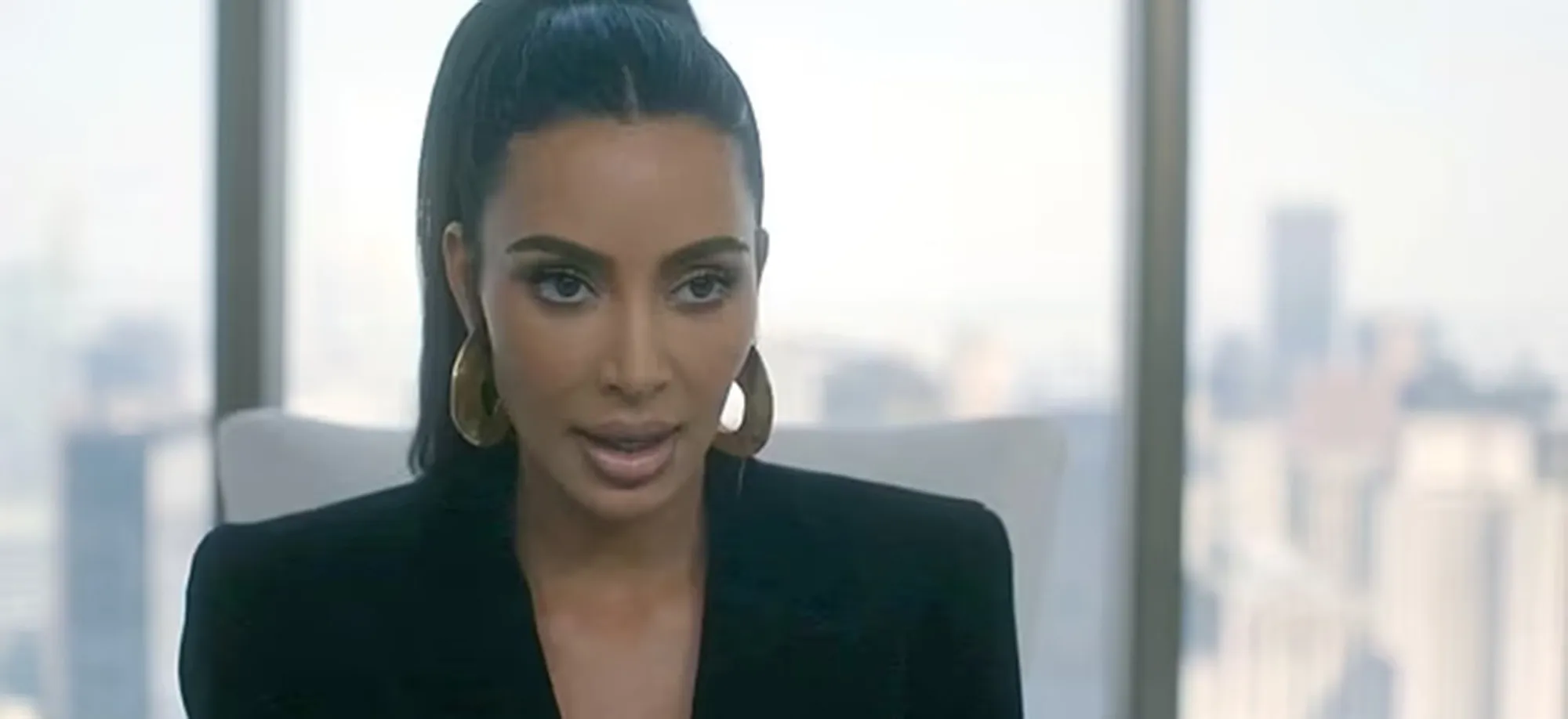 Kim Kardashian in a black jacket and gold earrings.
