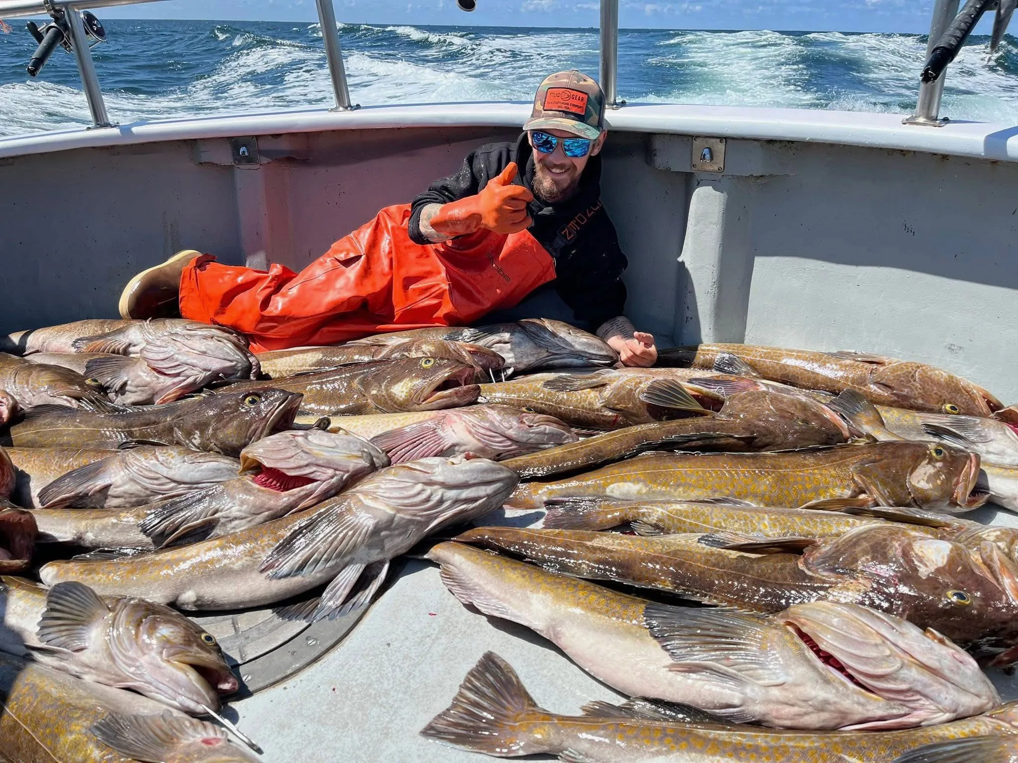 Todd Meadows on a boat surrounded by a large catch of fish, giving a thumbs up.