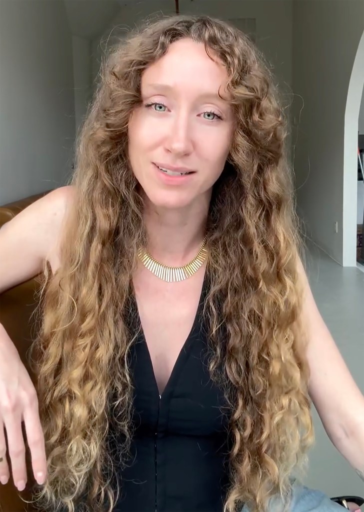 A woman with long, curly blonde hair and a gold necklace smiling at the camera.
