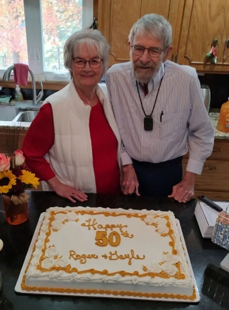 Gayle and Roger Wilson standing behind a cake celebrating their 50th anniversary.