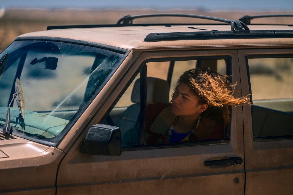 Zendaya as Rue Bennett in "Euphoria Season 3" looks out the window of a dusty car.
