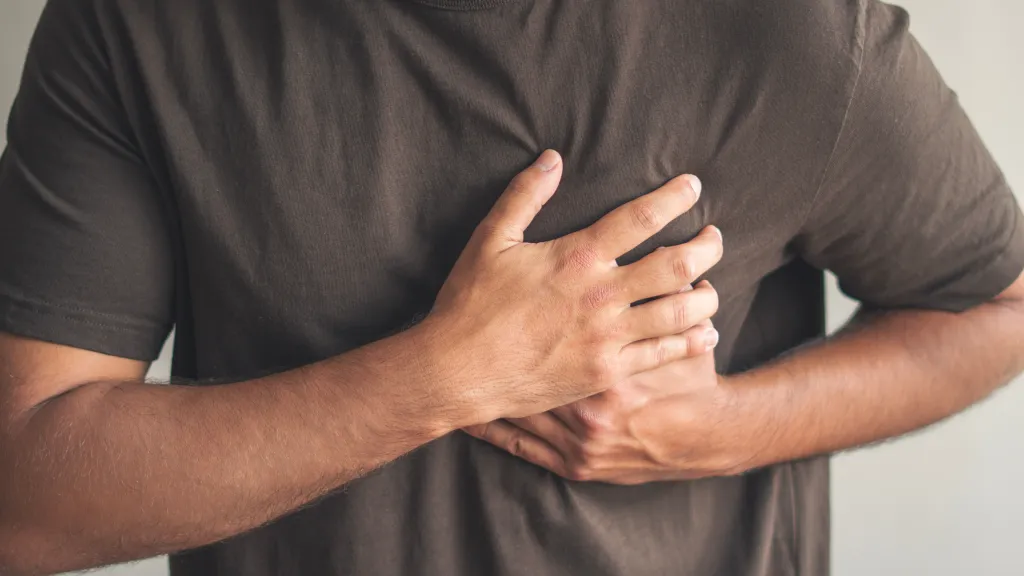 Man clutching his chest due to heart pain.