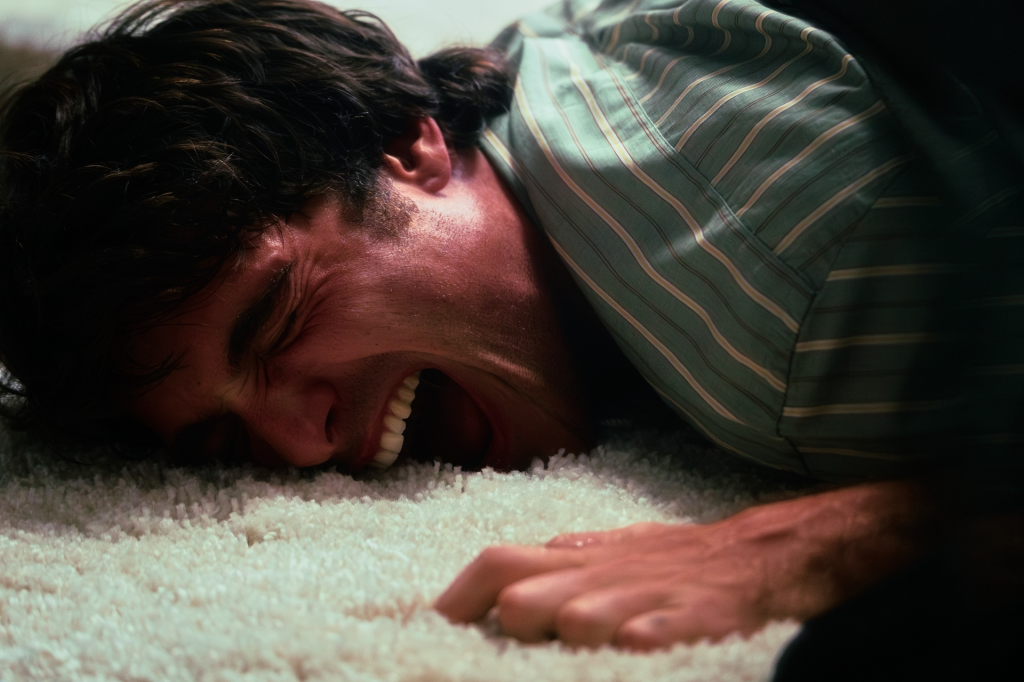 Man lying on a white rug, laughing or screaming.